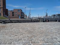 a brick walkway that leads to a boat dock in a harbor with buildings next to it