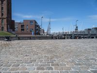 a brick walkway that leads to a boat dock in a harbor with buildings next to it