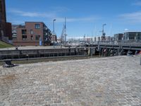 a brick walkway that leads to a boat dock in a harbor with buildings next to it