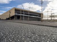 a long building on a side walk with brick in front of it and two people walking around the walkway