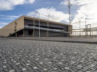 a long building on a side walk with brick in front of it and two people walking around the walkway