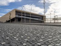 a long building on a side walk with brick in front of it and two people walking around the walkway