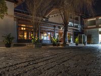 an empty cobblestone street in a historic city at night with people and shops