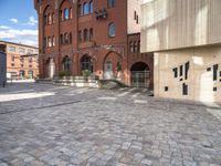 the brick street has a few steps leading up to several building with windows on them