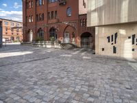 the brick street has a few steps leading up to several building with windows on them