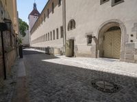 a cobblestone road next to some buildings and some trees, and a white fire hydrant