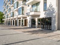 brick road in front of a modern apartment building with large windows on the outside and stone pavers on the sidewalk