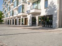 brick road in front of a modern apartment building with large windows on the outside and stone pavers on the sidewalk