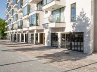 brick road in front of a modern apartment building with large windows on the outside and stone pavers on the sidewalk