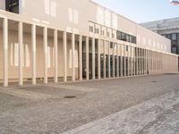 a room with columns near a building with light pouring through it and shadows in the windows