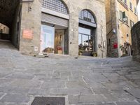 there are cobblestones in a city street, there is an old building behind them