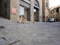 there are cobblestones in a city street, there is an old building behind them