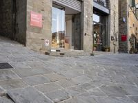 there are cobblestones in a city street, there is an old building behind them