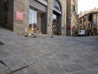 there are cobblestones in a city street, there is an old building behind them