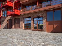 a cobbled sidewalk outside of a very tall red building with balconies and windows