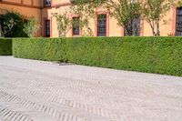 a cobbled sidewalk in front of a beautiful home with windows and bushes surrounding it