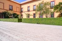 a cobbled sidewalk in front of a beautiful home with windows and bushes surrounding it