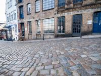 a cobbled - in parking area on the side of a brick building with blue doors