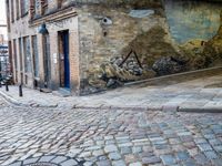 a cobbled - in parking area on the side of a brick building with blue doors