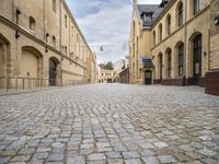 an alley that has a cobblestone street with old building and lampposts