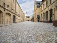 an alley that has a cobblestone street with old building and lampposts