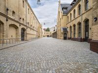 an alley that has a cobblestone street with old building and lampposts