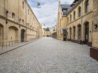 an alley that has a cobblestone street with old building and lampposts