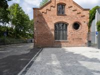 brick walkway that connects to the brick building with the arched window that surrounds it,