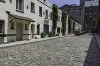 the sidewalk is lined with cobblestone brick buildings and parked cars outside each window