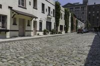 the sidewalk is lined with cobblestone brick buildings and parked cars outside each window