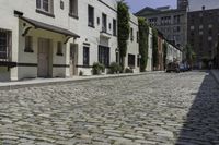 the sidewalk is lined with cobblestone brick buildings and parked cars outside each window