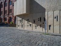 cobblestone driveway surrounded by modern buildings on sunny day with sun reflecting onto the windows