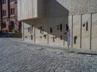 cobblestone driveway surrounded by modern buildings on sunny day with sun reflecting onto the windows