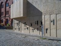 cobblestone driveway surrounded by modern buildings on sunny day with sun reflecting onto the windows