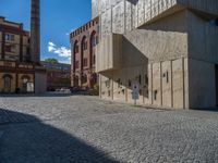 cobblestone driveway surrounded by modern buildings on sunny day with sun reflecting onto the windows