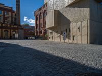 cobblestone driveway surrounded by modern buildings on sunny day with sun reflecting onto the windows