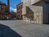 cobblestone driveway surrounded by modern buildings on sunny day with sun reflecting onto the windows