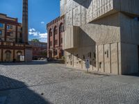 cobblestone driveway surrounded by modern buildings on sunny day with sun reflecting onto the windows