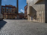 cobblestone driveway surrounded by modern buildings on sunny day with sun reflecting onto the windows