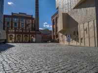 cobblestone driveway surrounded by modern buildings on sunny day with sun reflecting onto the windows