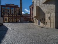 cobblestone driveway surrounded by modern buildings on sunny day with sun reflecting onto the windows