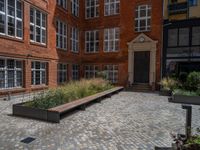 several plants sit in decorative concrete planters along the sidewalk of a building that is very modern