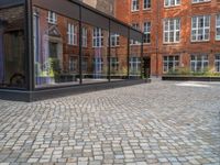 an empty parking lot with plants in the ground and on the side of the building, there is an enclosed area and windows