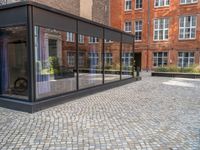 an empty parking lot with plants in the ground and on the side of the building, there is an enclosed area and windows