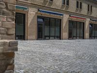 the sidewalk is paved with stones and has a bench in front of it, with no people inside