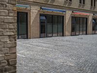 the sidewalk is paved with stones and has a bench in front of it, with no people inside