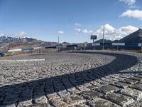 a car sitting on a cobblestone parking lot with mountains in the background,