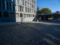 a cobblestone path passes through an old building in the sun, with one end showing