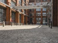 a cobblestone paved courtyard with brick floors and a bridge for traffic to pass