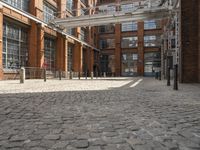 a cobblestone paved courtyard with brick floors and a bridge for traffic to pass